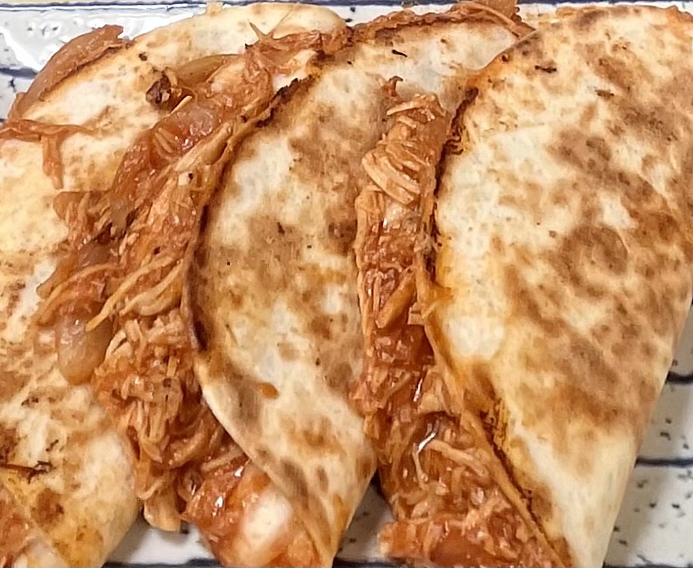 Pila de quesadillas a la parrilla cortadas por la mitad mostrando queso fundido y relleno de pollo