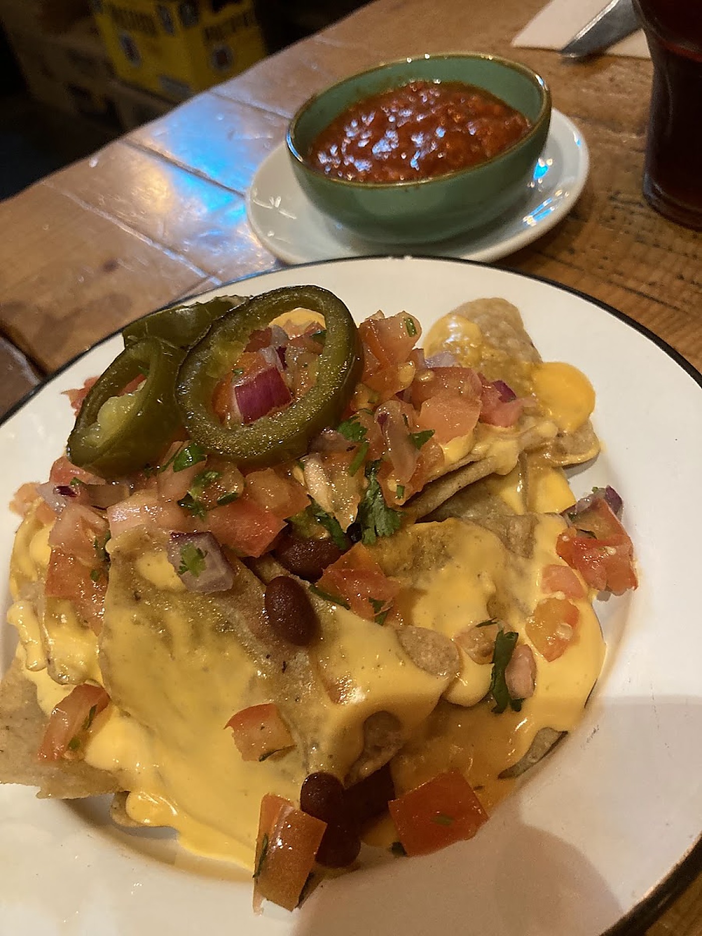 Nachos con salsa de queso, jalapeños y pico de gallo junto a tazón de sopa de frijoles